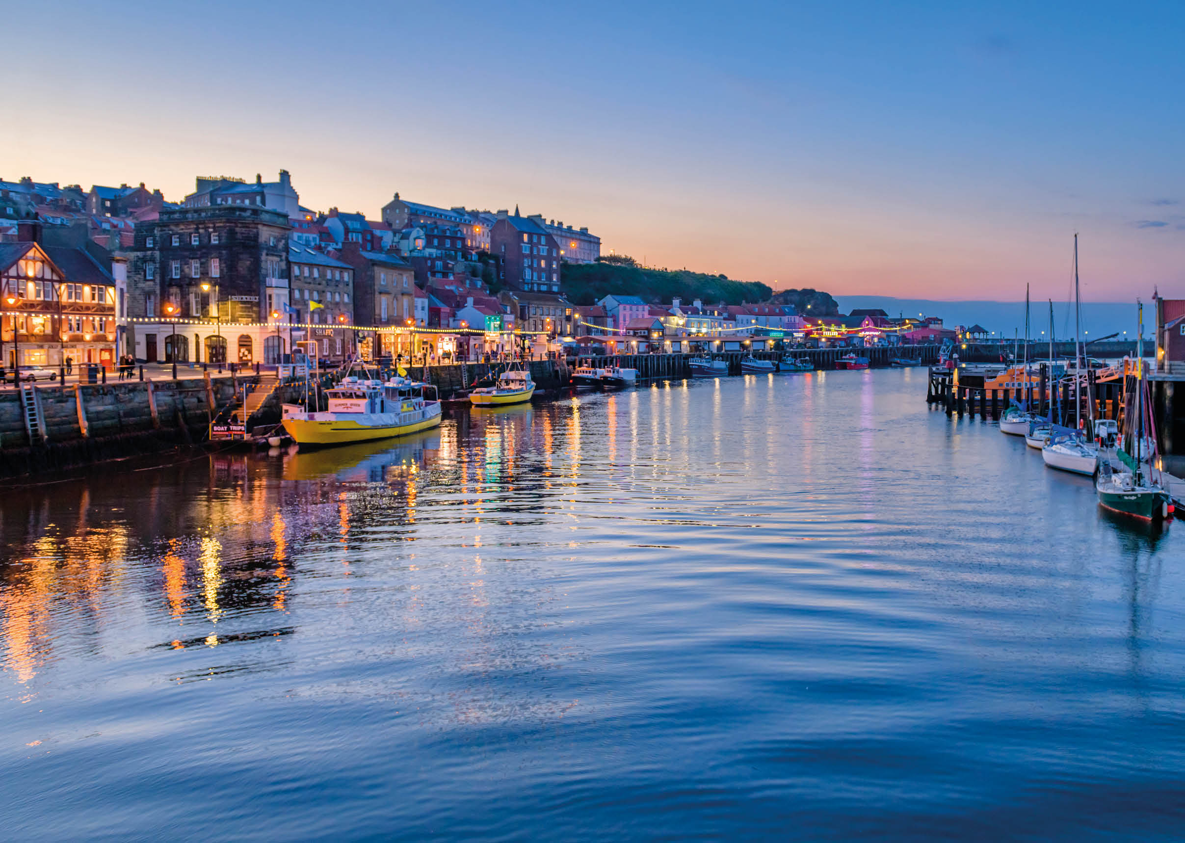 River Esk flowing through Whitby harbour in the evening showing reflections from the town